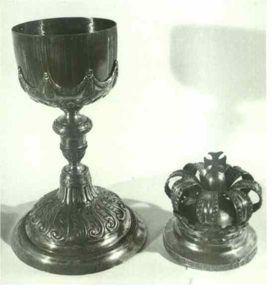 A silver liturgical chalice with a richly decorated base and bowl and a crown of similar style, placed side by side.