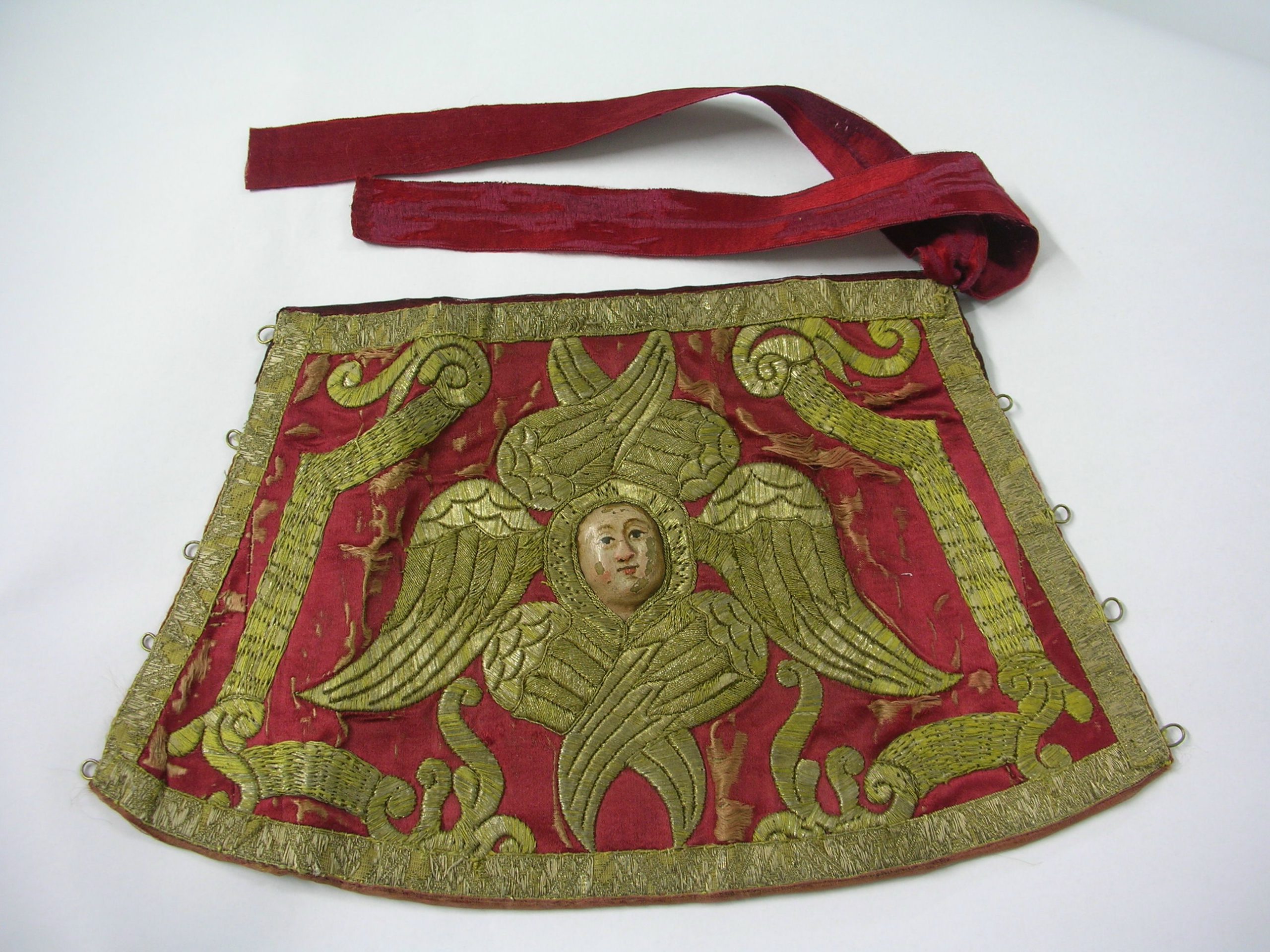 Red liturgical cloth with gold-embroidered seraph and red ribbon.