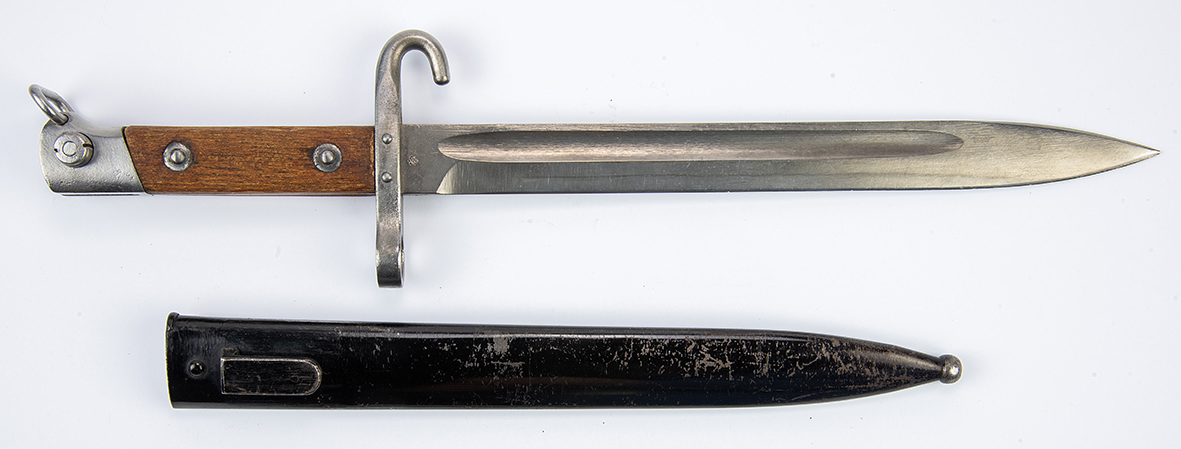 A bayonet with a wooden handle and metal scabbard, used as a melee weapon mounted on a rifle.