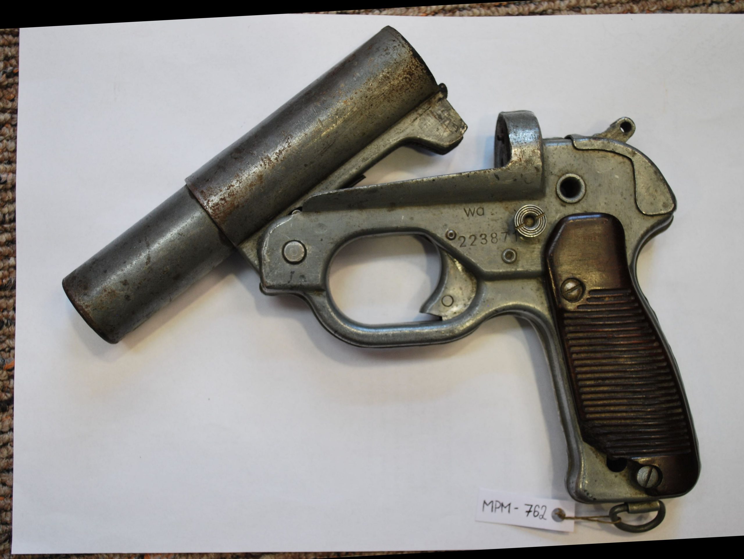 Flame pistol with a metal body and a brown, ribbed grip.