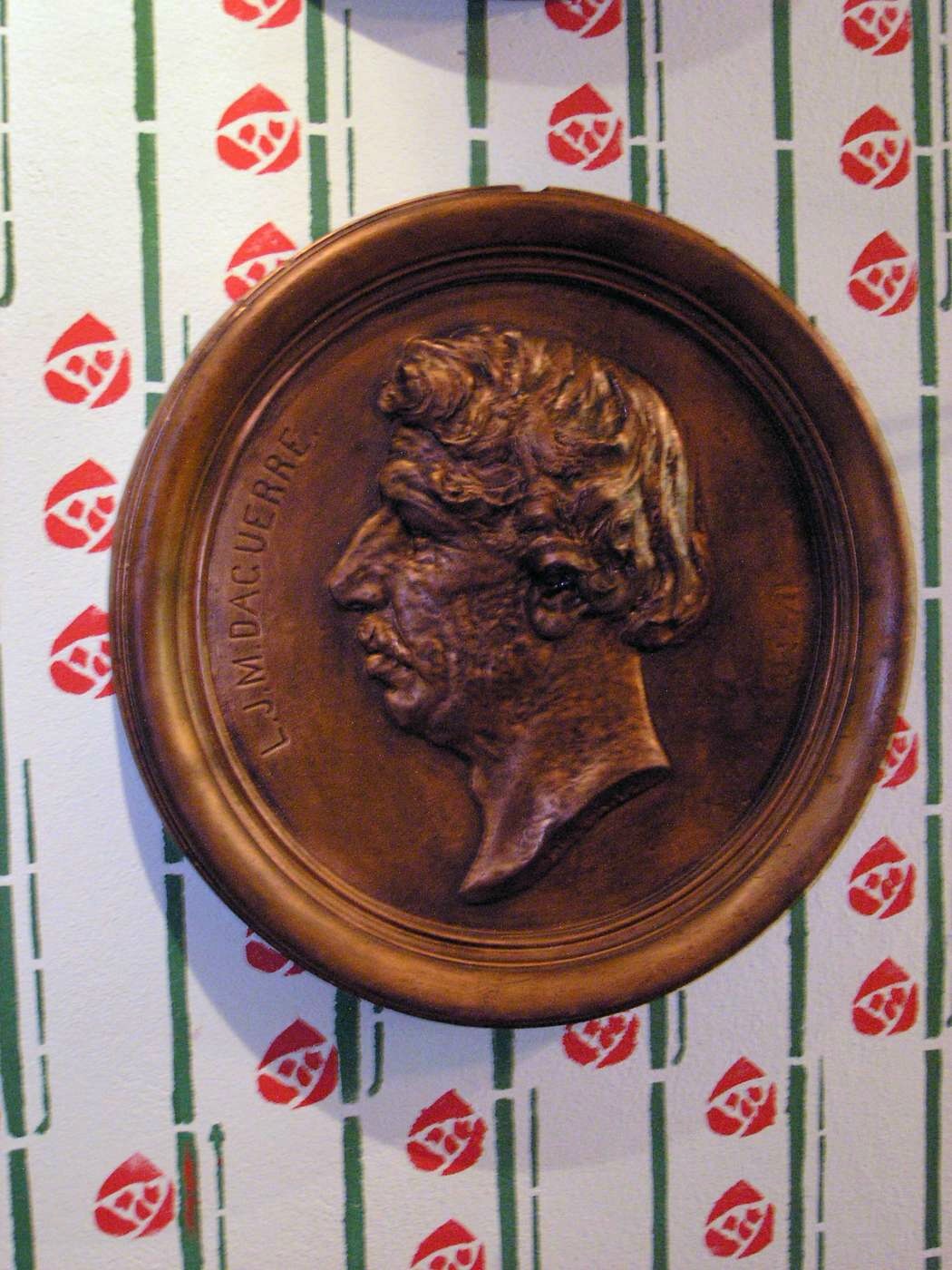 Bronze medallion with a profile of a man on a decorative wall.