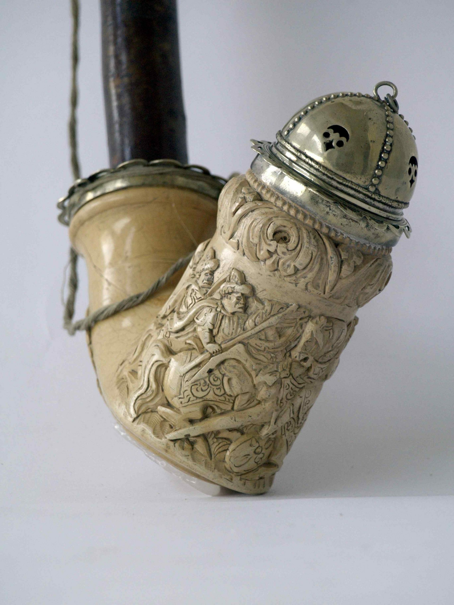 Pipe with a carved, richly decorated bone bowl and metal cap.