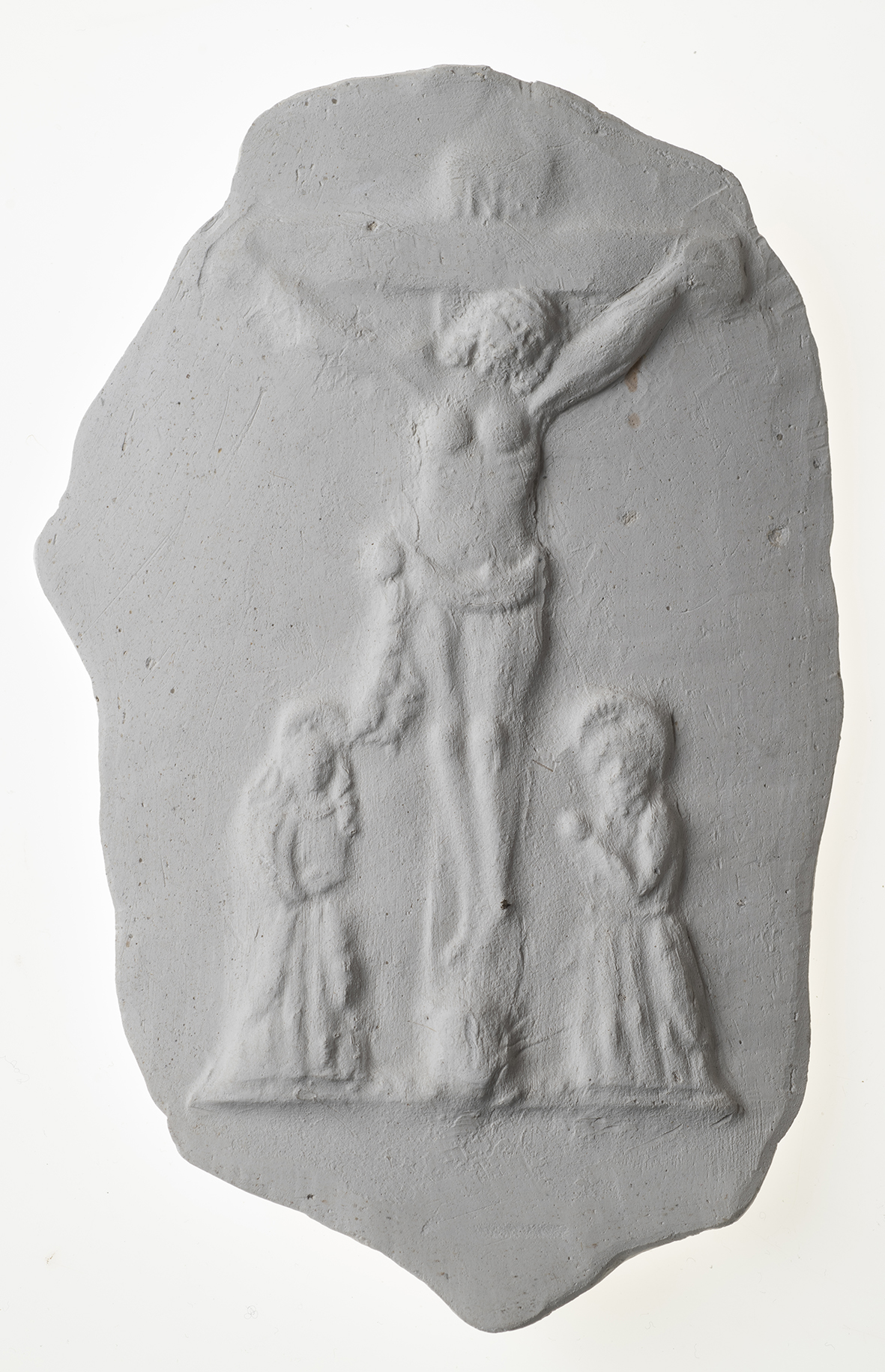 A plaster cast depicting a crucifixion scene with three figures in relief.