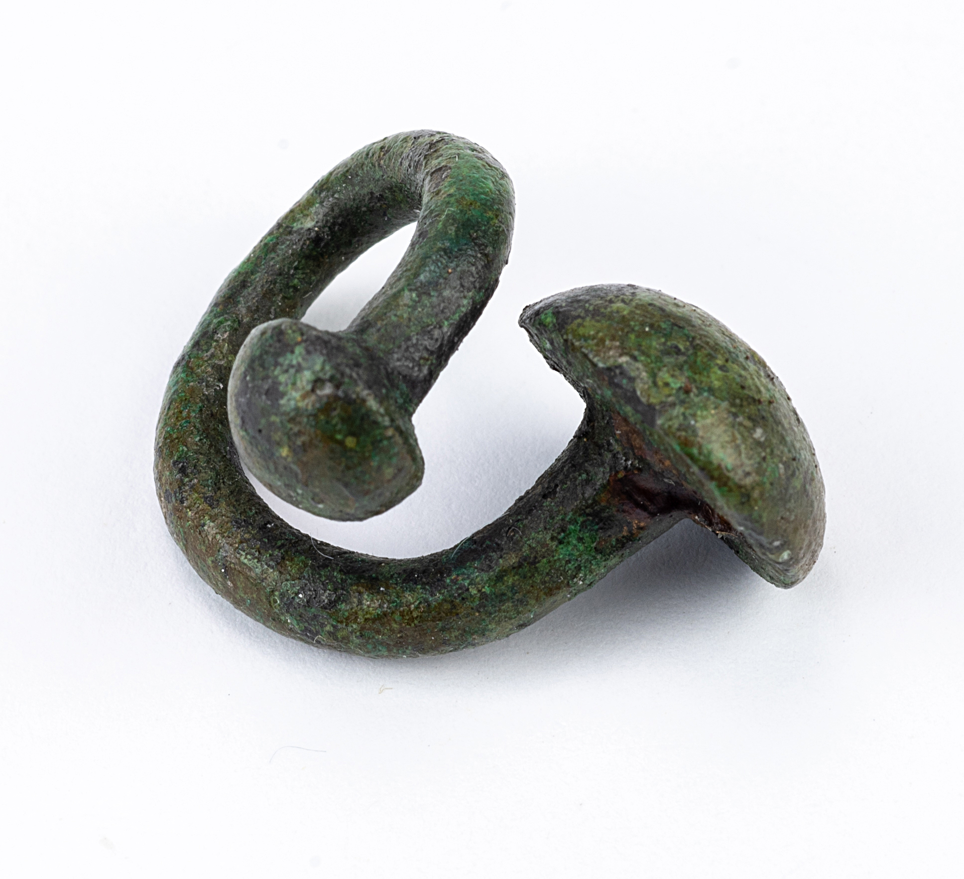 An ancient bronze brooch in the shape of a double hook with rounded ends.