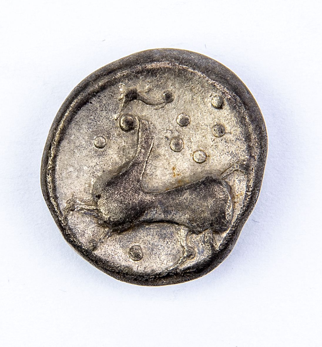 Ancient coin with the image of a stylized animal, probably a horse.