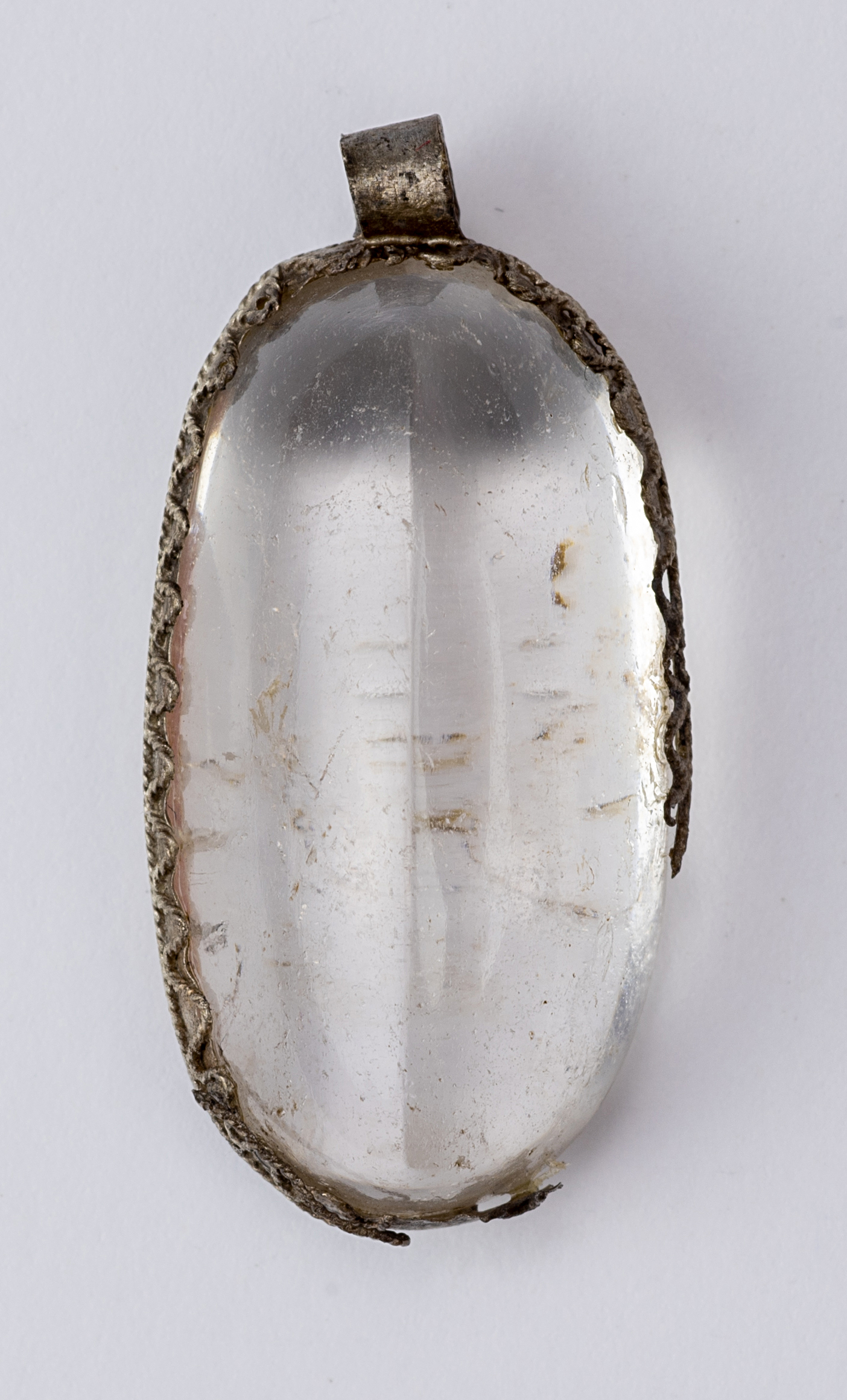 An oval medieval pendant with a transparent stone set in metal.