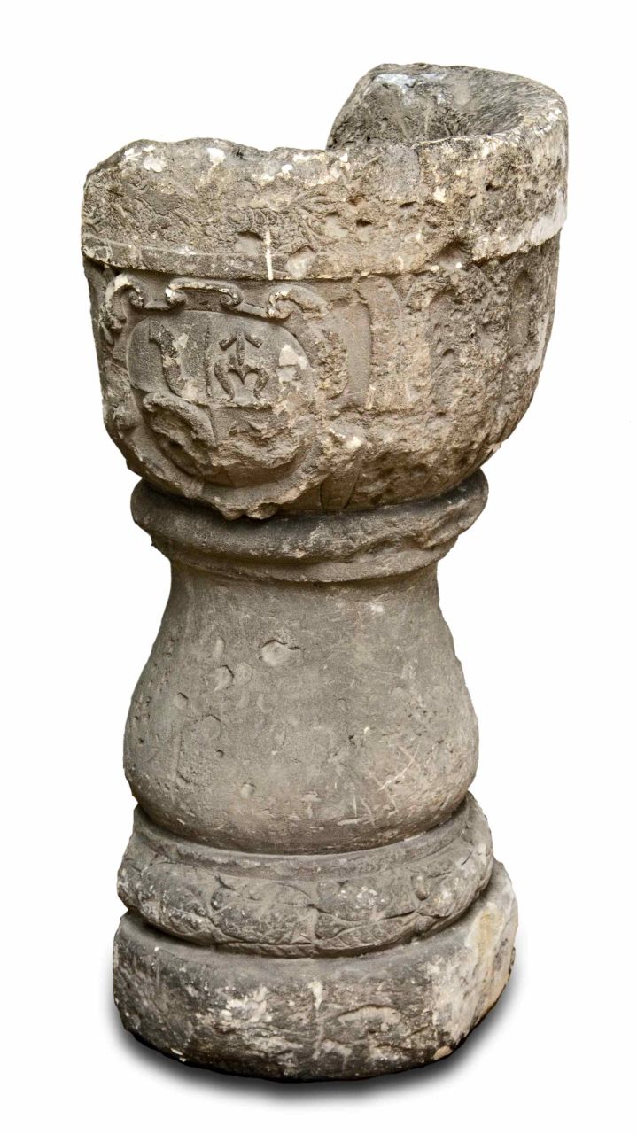 Stone baptismal font with decorative relief, a fragment of historical sacred equipment.