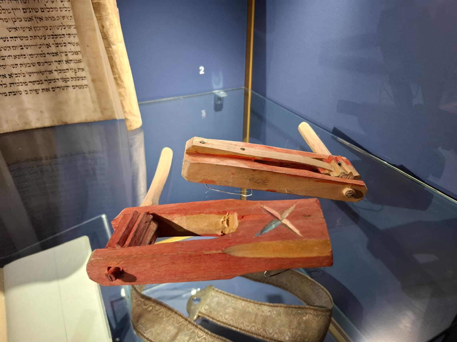 A wooden shofar in a museum display case, with visible signs of use and painted details.