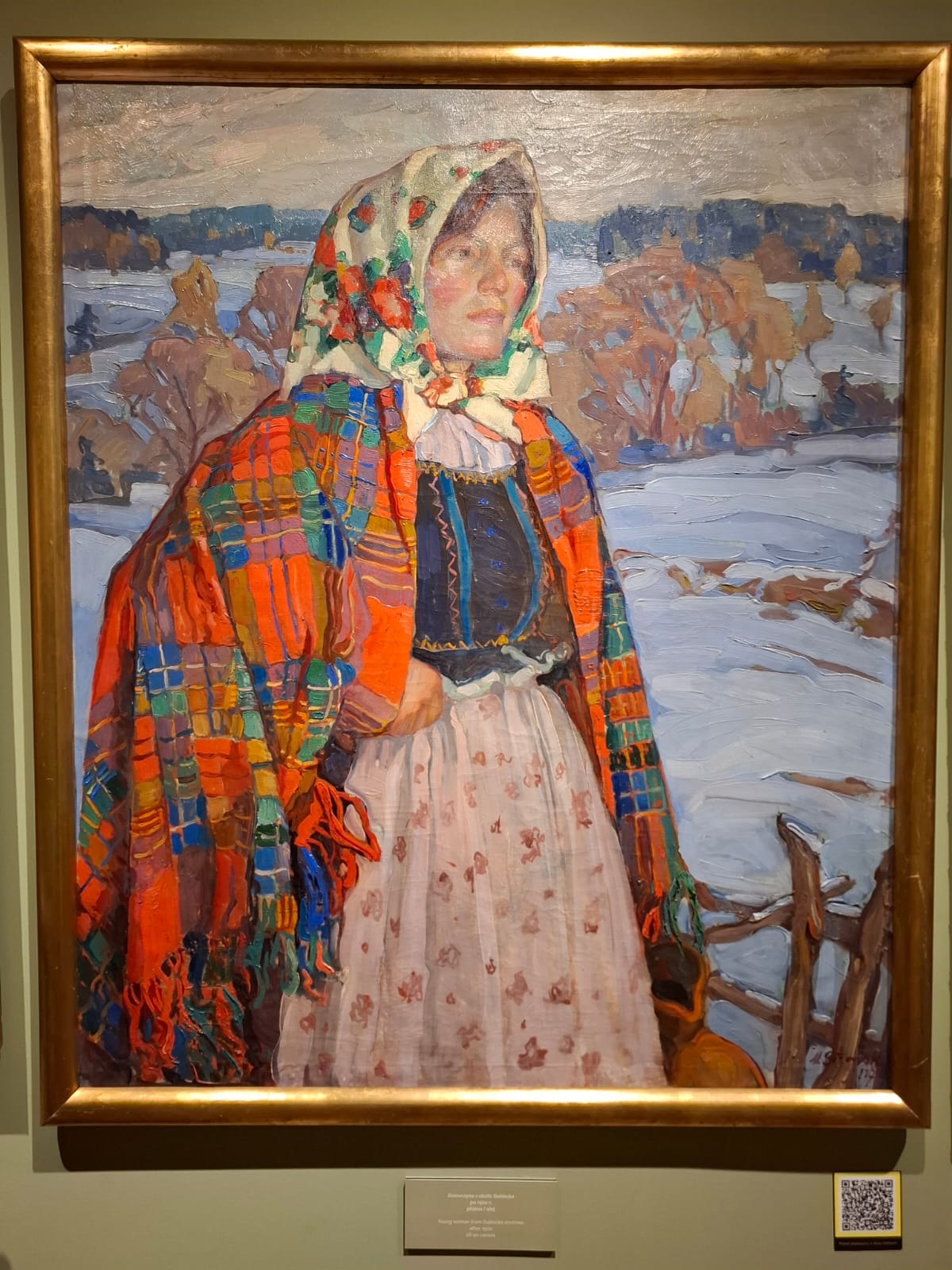 A painting depicting a woman in a colorful folk costume standing in a winter landscape, painted in an expressive style.