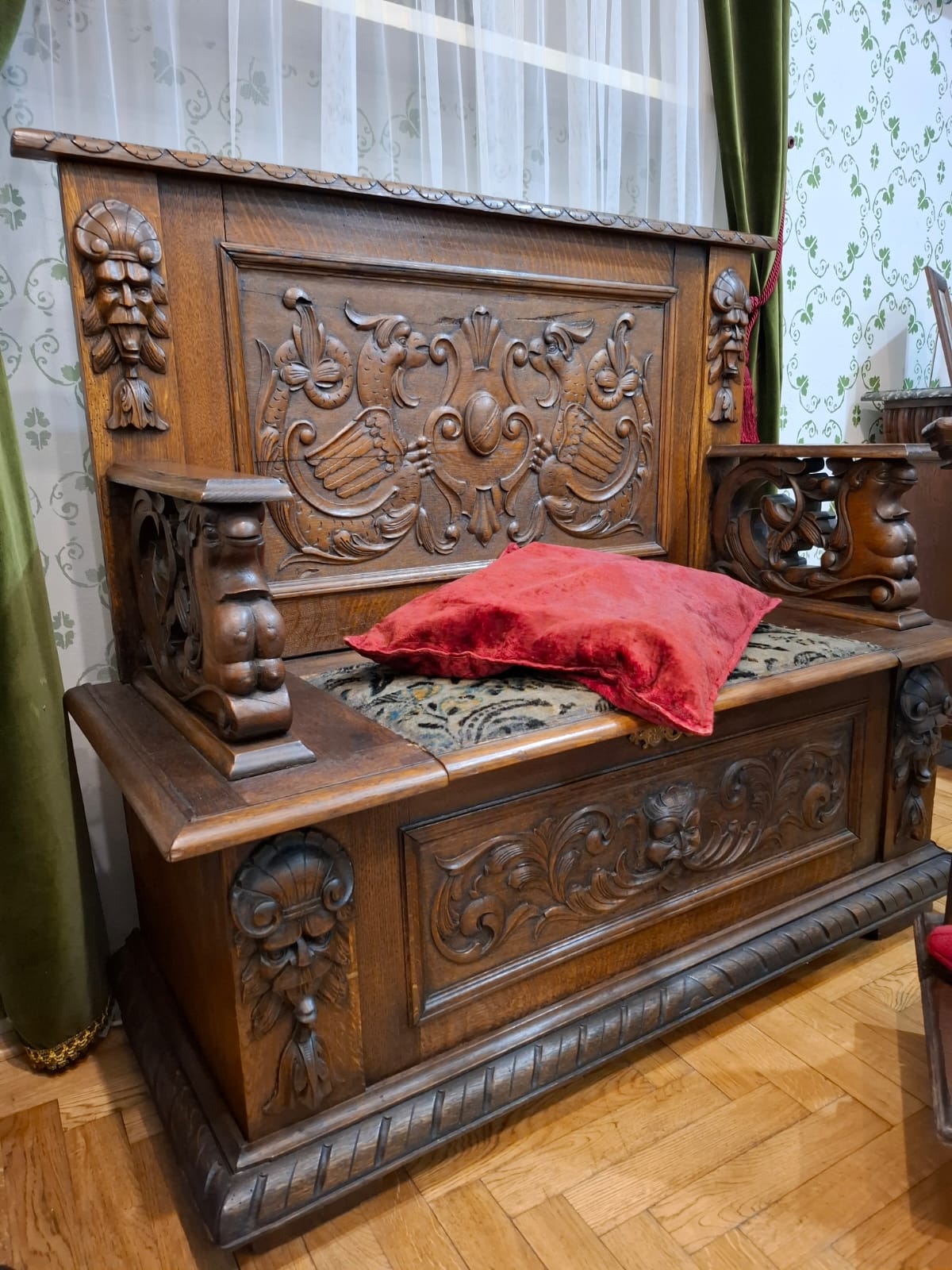A richly carved wooden bench with a backrest, an element of the historical furnishings of the museum interior.